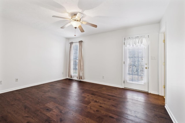 spare room with baseboards, a ceiling fan, and dark wood-type flooring