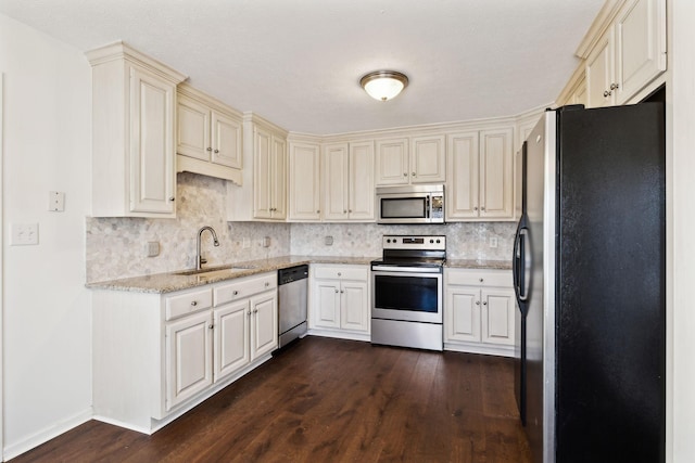 kitchen with appliances with stainless steel finishes, dark wood-type flooring, a sink, and tasteful backsplash