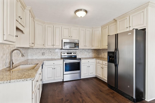 kitchen with decorative backsplash, dark wood finished floors, appliances with stainless steel finishes, light stone countertops, and a sink