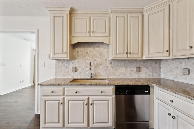 kitchen with decorative backsplash, dishwasher, light stone counters, cream cabinetry, and a sink