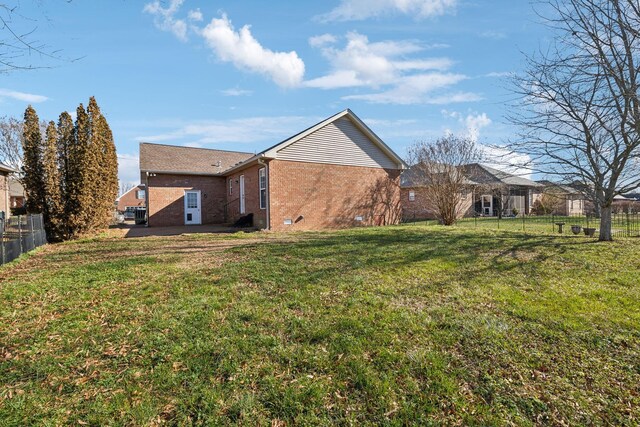 exterior space featuring crawl space, brick siding, fence, and a lawn