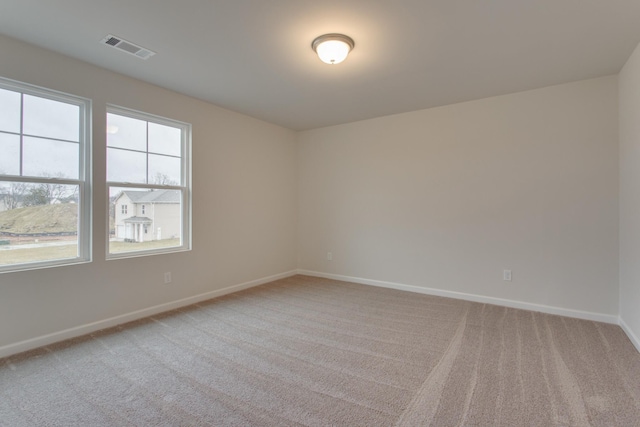 unfurnished room featuring visible vents, light carpet, and baseboards