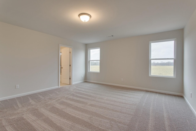 spare room featuring baseboards, visible vents, and light colored carpet