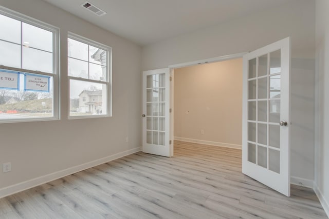 empty room featuring french doors, wood finished floors, visible vents, and baseboards