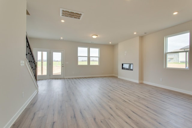 unfurnished living room featuring recessed lighting, visible vents, light wood finished floors, and stairs