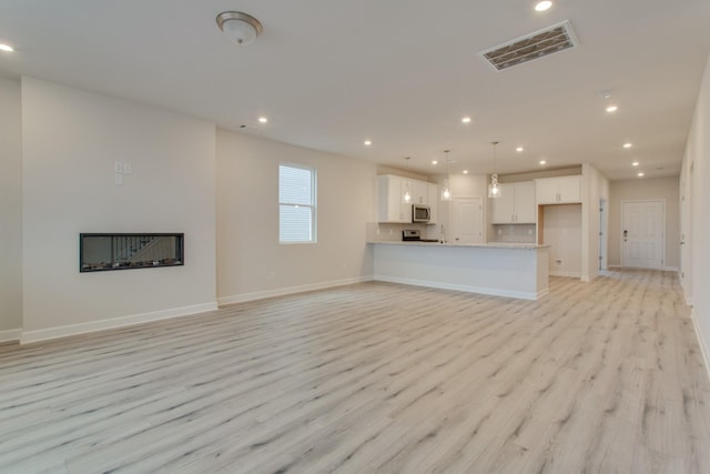 unfurnished living room featuring recessed lighting, visible vents, light wood-style flooring, and baseboards