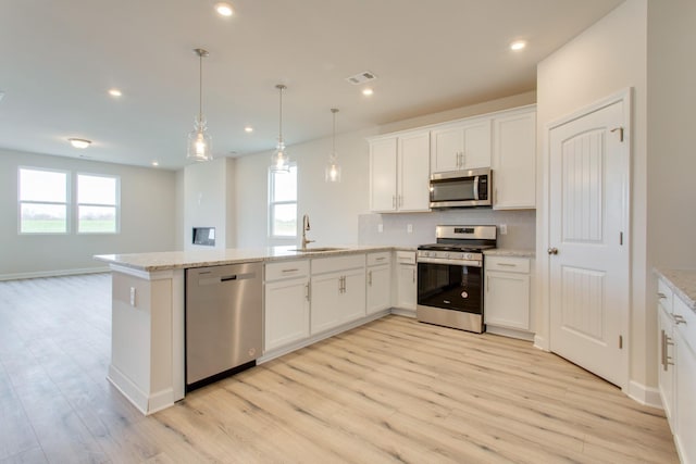 kitchen featuring light wood finished floors, visible vents, appliances with stainless steel finishes, a peninsula, and a sink