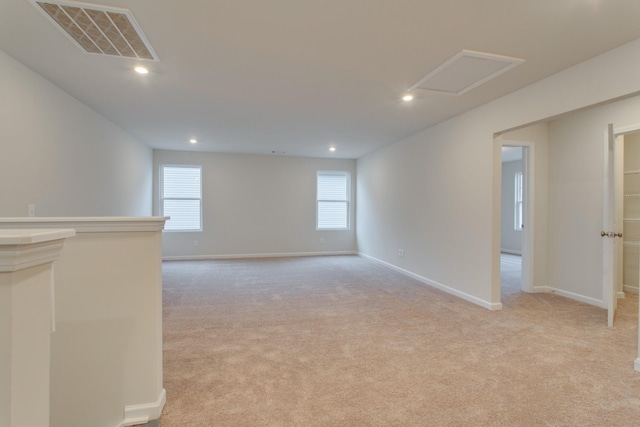 empty room with light carpet, attic access, visible vents, and baseboards