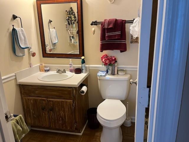 bathroom with parquet floors, toilet, and vanity