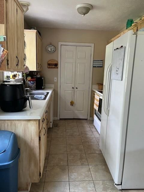 kitchen featuring white appliances, light tile patterned floors, sink, and light brown cabinets