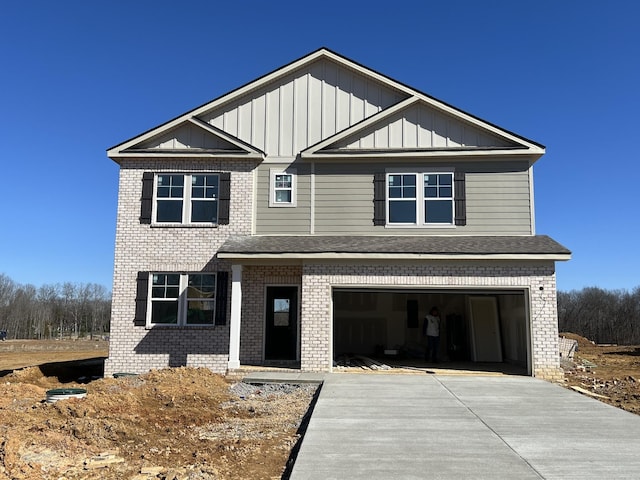 view of front of house featuring board and batten siding, brick siding, driveway, and an attached garage