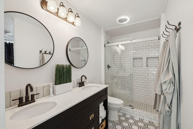 bathroom with toilet, tiled shower, tile patterned flooring, and vanity