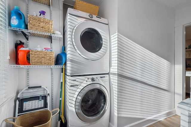 laundry room with hardwood / wood-style flooring and stacked washer and clothes dryer