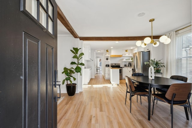 dining room with light hardwood / wood-style floors, a chandelier, and beamed ceiling