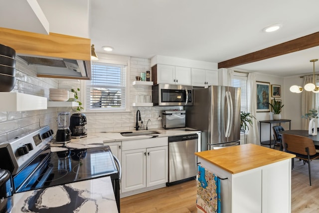 kitchen featuring hanging light fixtures, a center island, appliances with stainless steel finishes, and white cabinetry