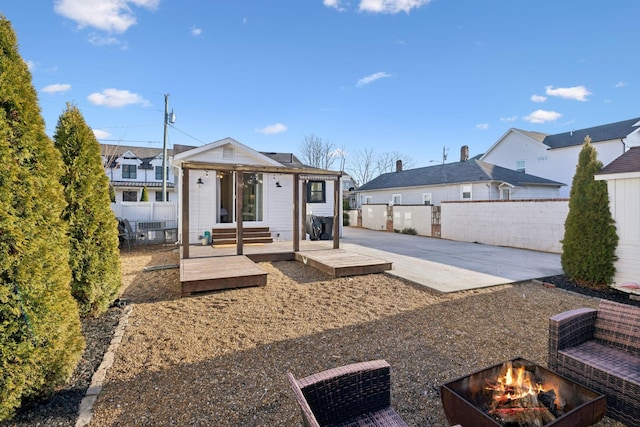 back of property featuring a patio area, an outdoor structure, and an outdoor fire pit