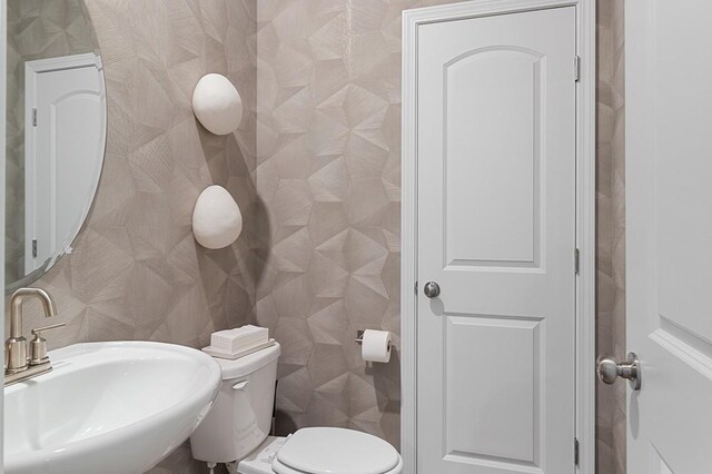 half bathroom featuring toilet, tile walls, and a sink