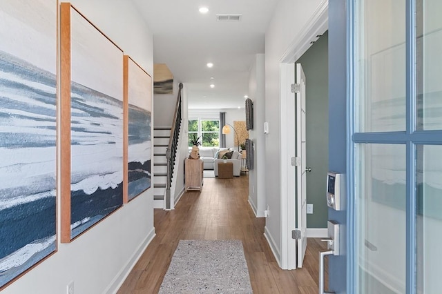 corridor featuring recessed lighting, wood finished floors, visible vents, baseboards, and stairway