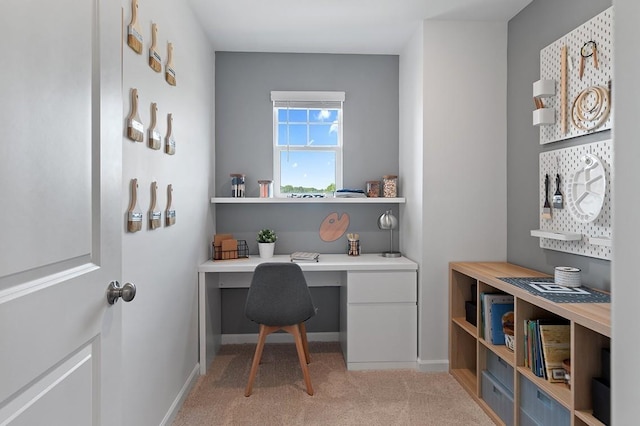 office space with light carpet, baseboards, and built in desk