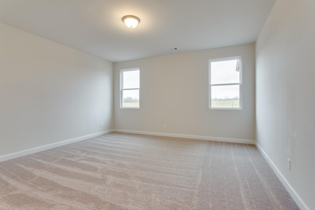 spare room featuring light colored carpet and baseboards