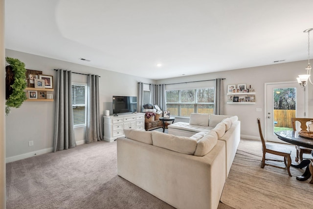 carpeted living room with an inviting chandelier