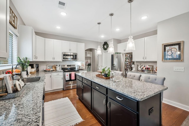 kitchen featuring white cabinetry, a center island, sink, appliances with stainless steel finishes, and pendant lighting