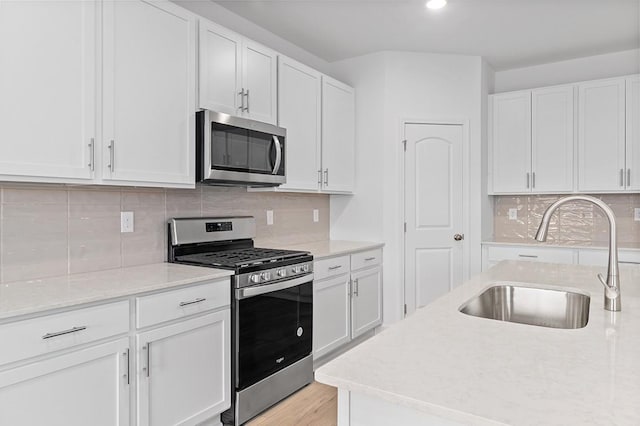 kitchen with white cabinets, backsplash, stainless steel appliances, and a sink