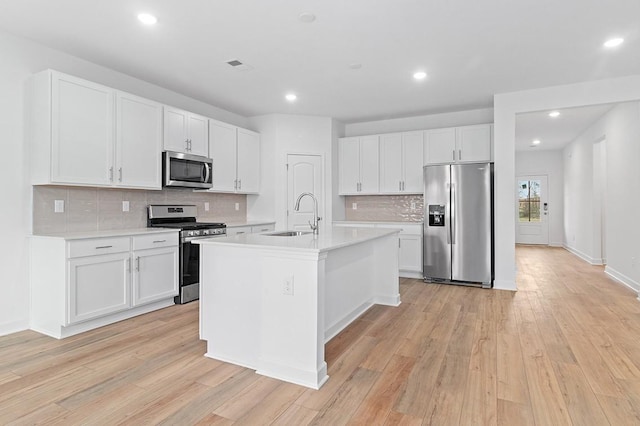 kitchen with light countertops, appliances with stainless steel finishes, light wood-style floors, white cabinetry, and a sink