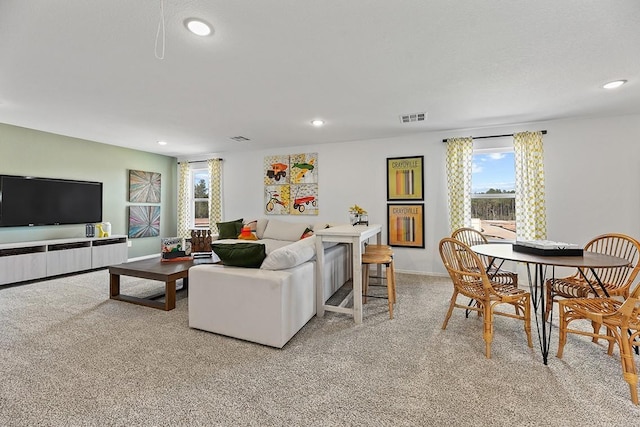 living area with baseboards, recessed lighting, visible vents, and light colored carpet