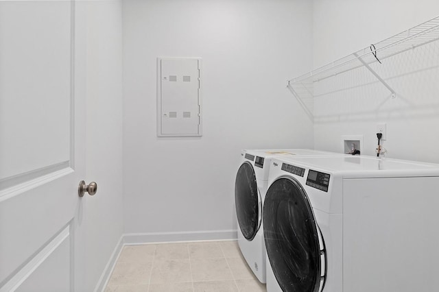 washroom with light tile patterned floors, laundry area, washing machine and clothes dryer, and baseboards