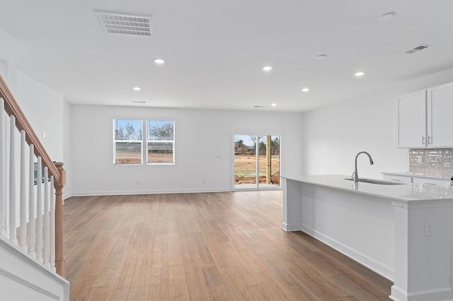 kitchen with recessed lighting, light countertops, visible vents, light wood-style flooring, and a sink