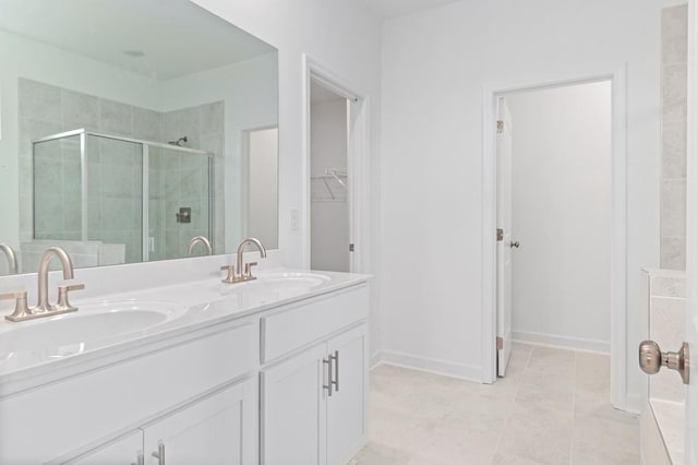 bathroom with a stall shower, a sink, a spacious closet, and double vanity