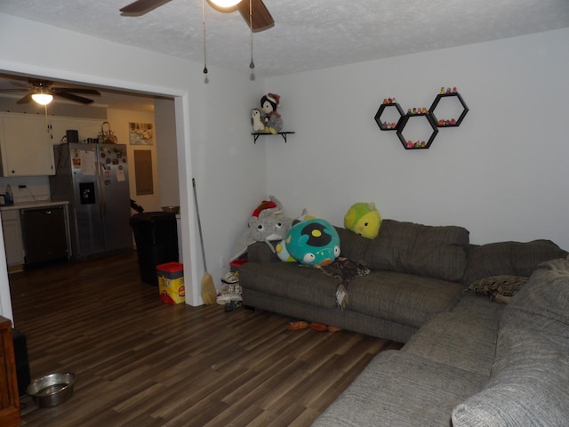 living room featuring ceiling fan, dark wood-type flooring, and a textured ceiling