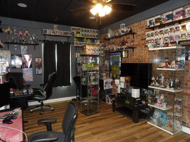 office area with brick wall, ceiling fan, and wood-type flooring