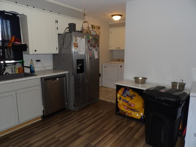 kitchen featuring washing machine and dryer, white cabinetry, sink, appliances with stainless steel finishes, and dark hardwood / wood-style floors