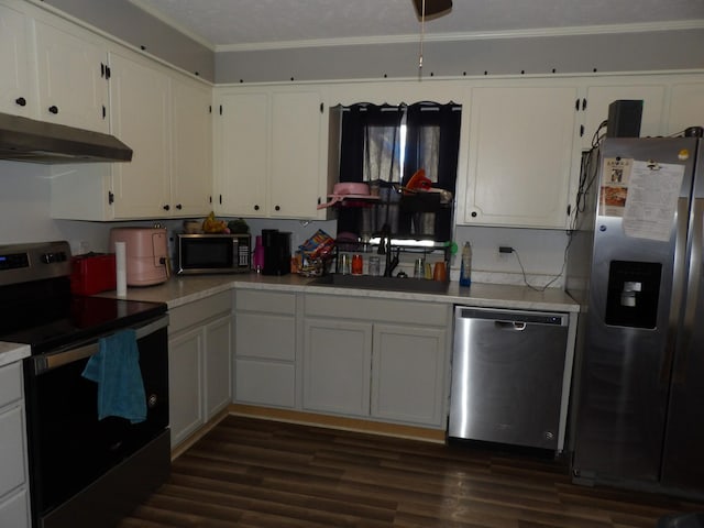 kitchen featuring appliances with stainless steel finishes, sink, white cabinetry, dark hardwood / wood-style flooring, and ornamental molding