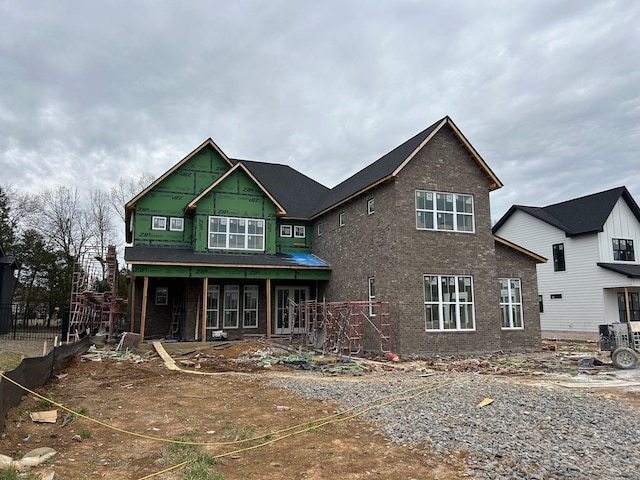 view of front of property featuring brick siding, a porch, and fence