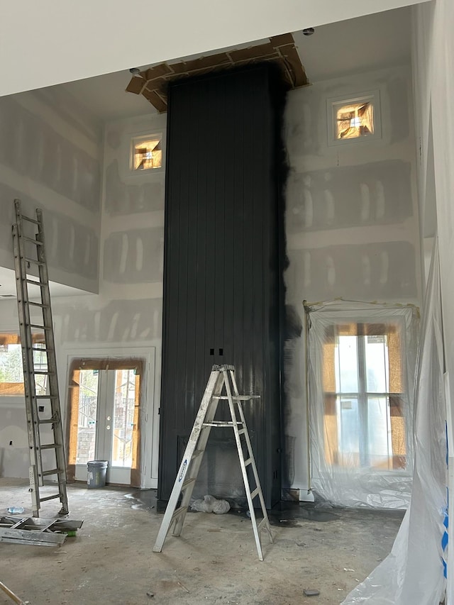 unfurnished living room featuring a healthy amount of sunlight, french doors, and a towering ceiling