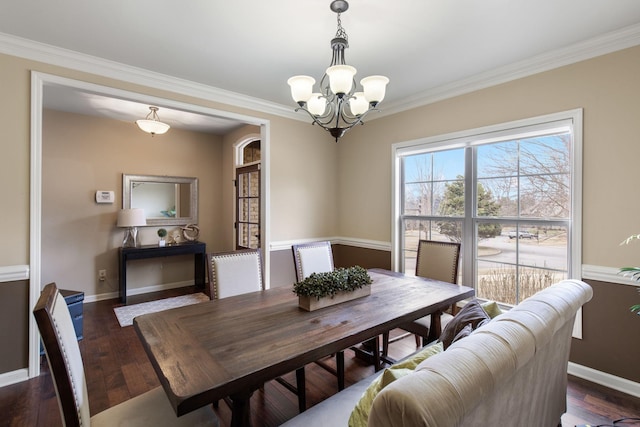 dining area with ornamental molding, dark hardwood / wood-style floors, and an inviting chandelier