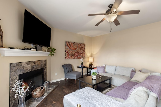 living room with a high end fireplace, ceiling fan, and dark wood-type flooring