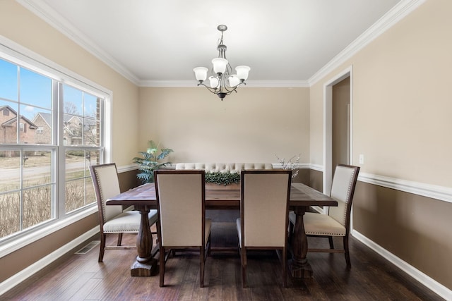 dining room with ornamental molding, dark hardwood / wood-style floors, and an inviting chandelier