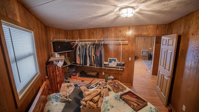 interior space with light hardwood / wood-style flooring, a textured ceiling, and wooden walls