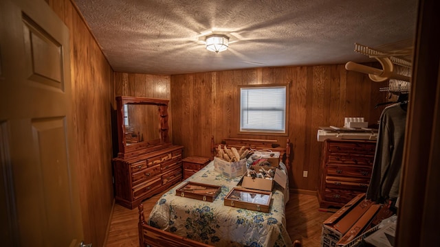 bedroom with a textured ceiling, wooden walls, and wood-type flooring