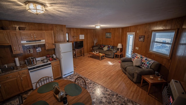 kitchen featuring heating unit, white appliances, a textured ceiling, hardwood / wood-style floors, and wooden walls