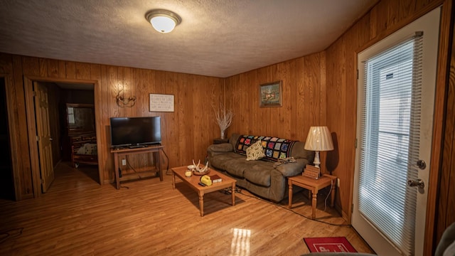 living room featuring wooden walls, a textured ceiling, and hardwood / wood-style floors