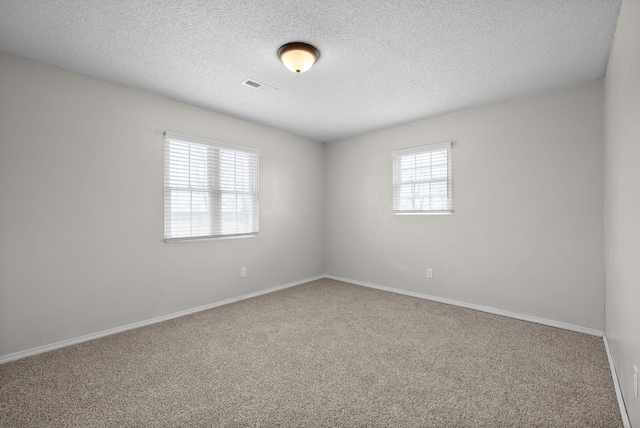 carpeted empty room with a textured ceiling