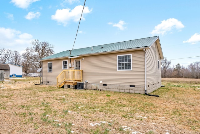 rear view of house featuring central air condition unit and a yard