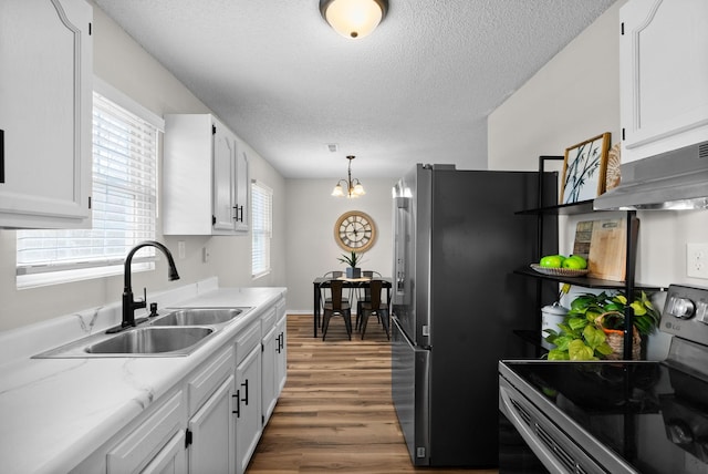 kitchen with sink, appliances with stainless steel finishes, white cabinetry, and decorative light fixtures