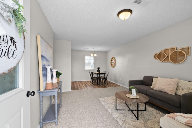 living room with a textured ceiling, carpet floors, and an inviting chandelier