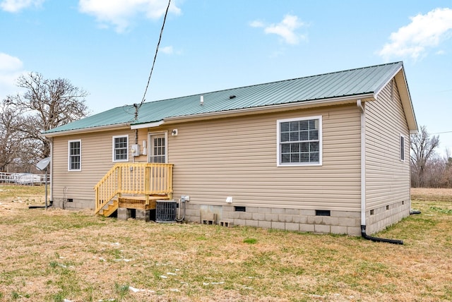 rear view of property featuring central air condition unit and a lawn